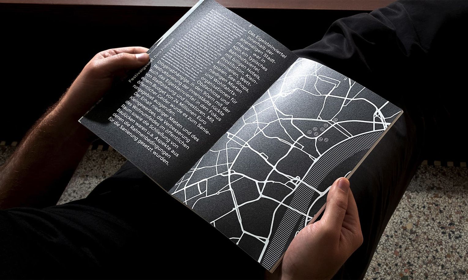 Opened book with two hands with black and white map and typography